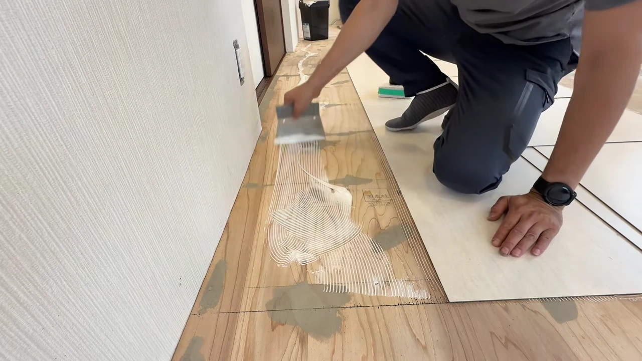 床にフロアタイルを一枚ずつ合わせる作業風景
